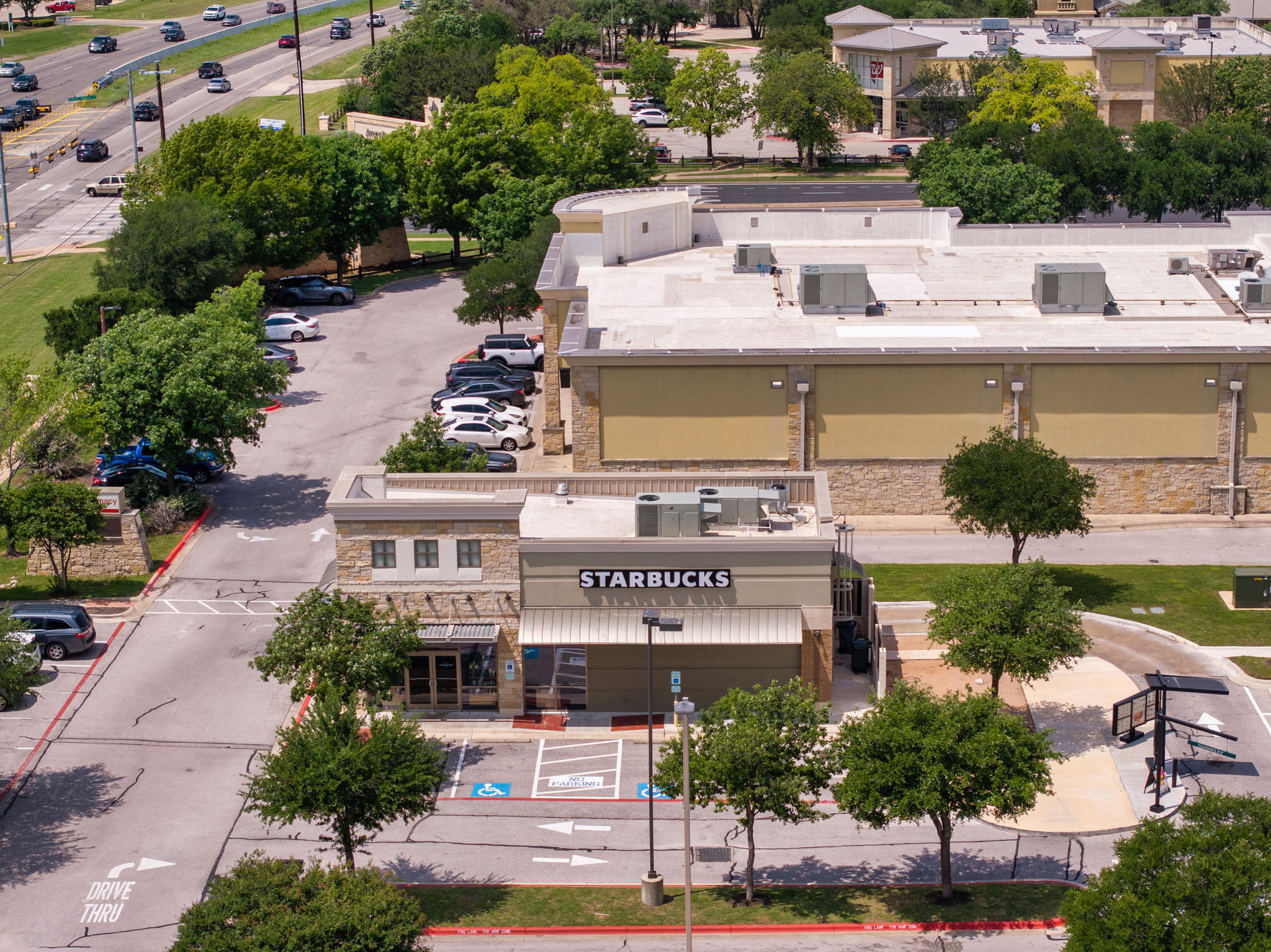 14815 Avery Ranch Boulevard, Unit 1401 Austin, TX 78717 - Photo 27 of 38 Commercial building featuring stone and stucco exterior finishes, a flat roof, and an integrated drive-thru