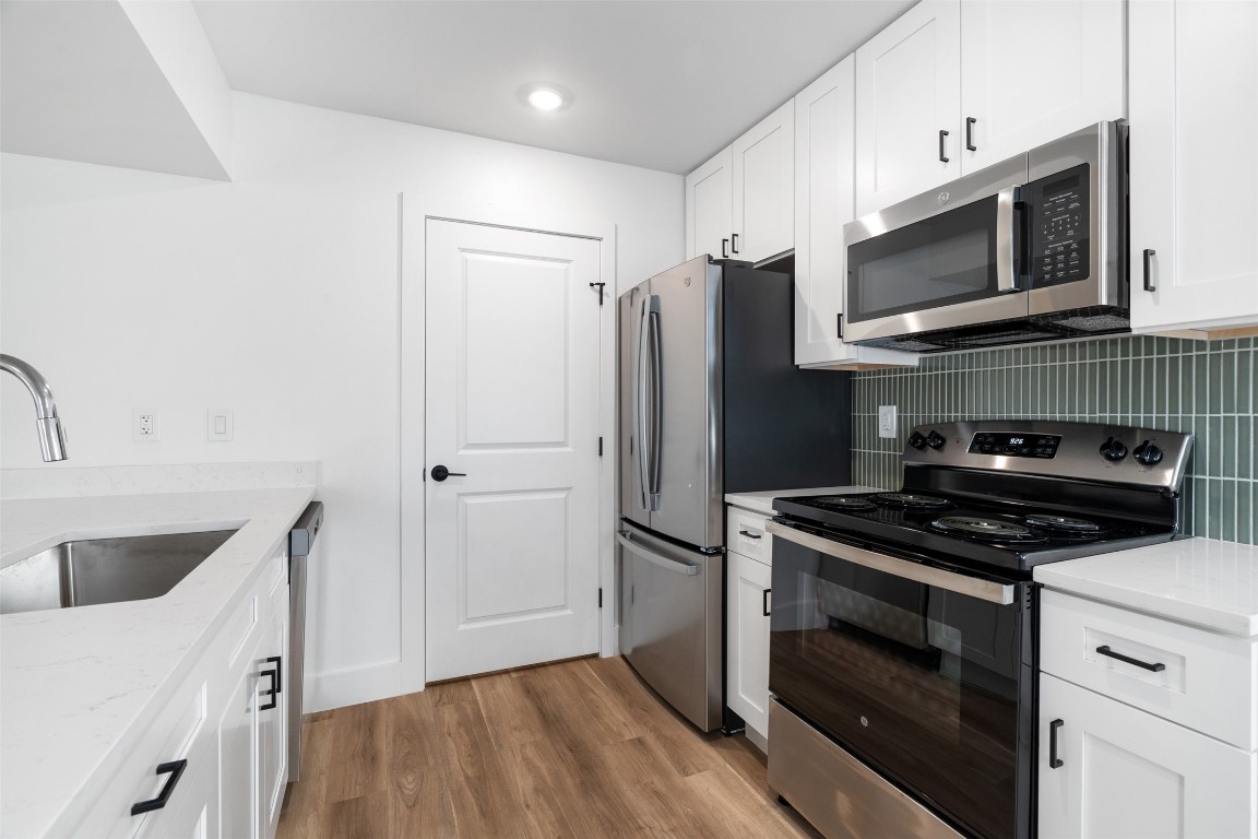 1901 Hearthstone Drive, Unit D Austin, TX 78757 - Photo 11 of 30 a kitchen with stainless steel appliances a stove a microwave and a hard wood floor