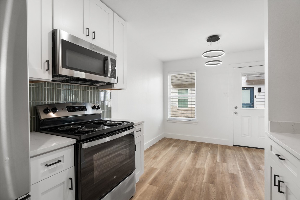 1901 Hearthstone Drive, Unit D Austin, TX 78757 - Photo 14 of 30 a kitchen with white cabinets stainless steel appliances and sink