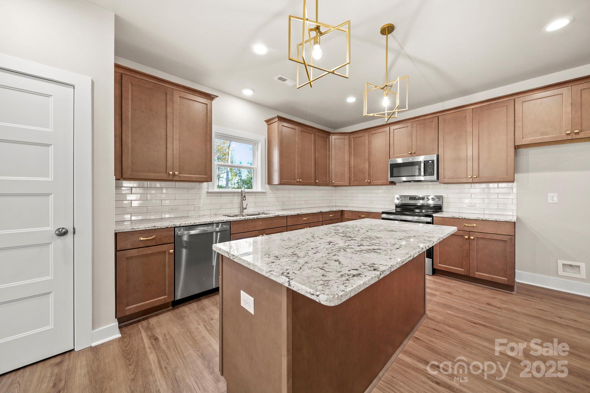2601 Plyler Mill Road Monroe, NC 28112 - Photo 2 of 23 a kitchen with kitchen island granite countertop wooden cabinets a stove a sink and a center island