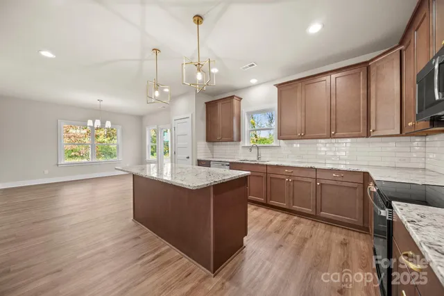 a kitchen with kitchen island granite countertop a sink a counter space appliances and cabinets