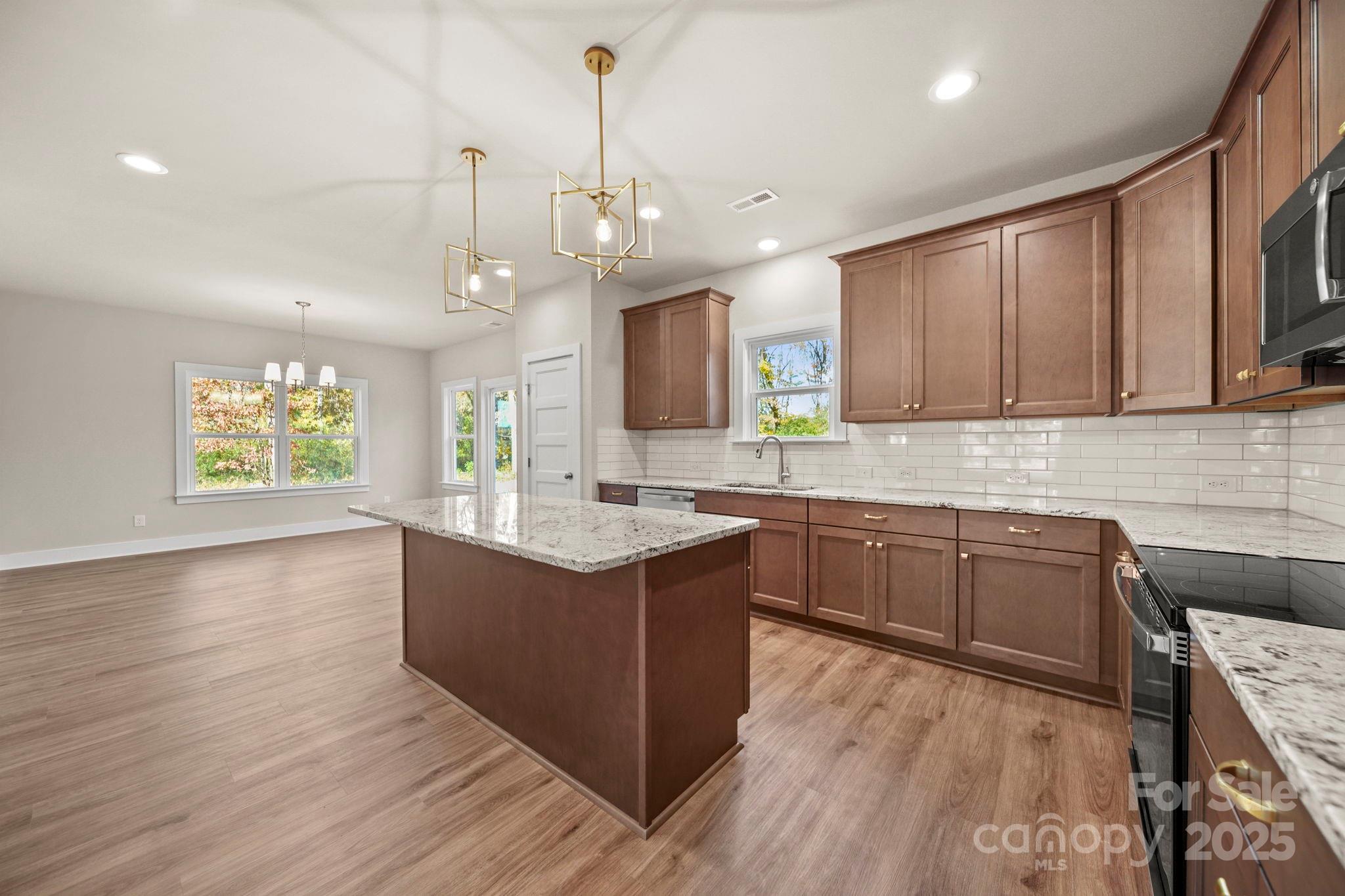 2601 Plyler Mill Road Monroe, NC 28112 - Photo 9 of 23 a kitchen with kitchen island granite countertop a sink cabinets and wooden floor