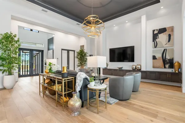 a living room with furniture a flat screen tv and a chandelier