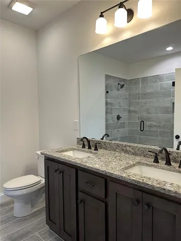 a bathroom with a granite countertop sink a toilet and a mirror