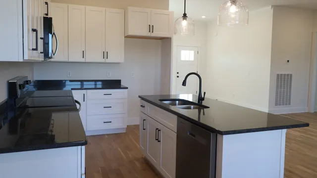 a kitchen with stainless steel appliances granite countertop a stove a sink and white cabinets