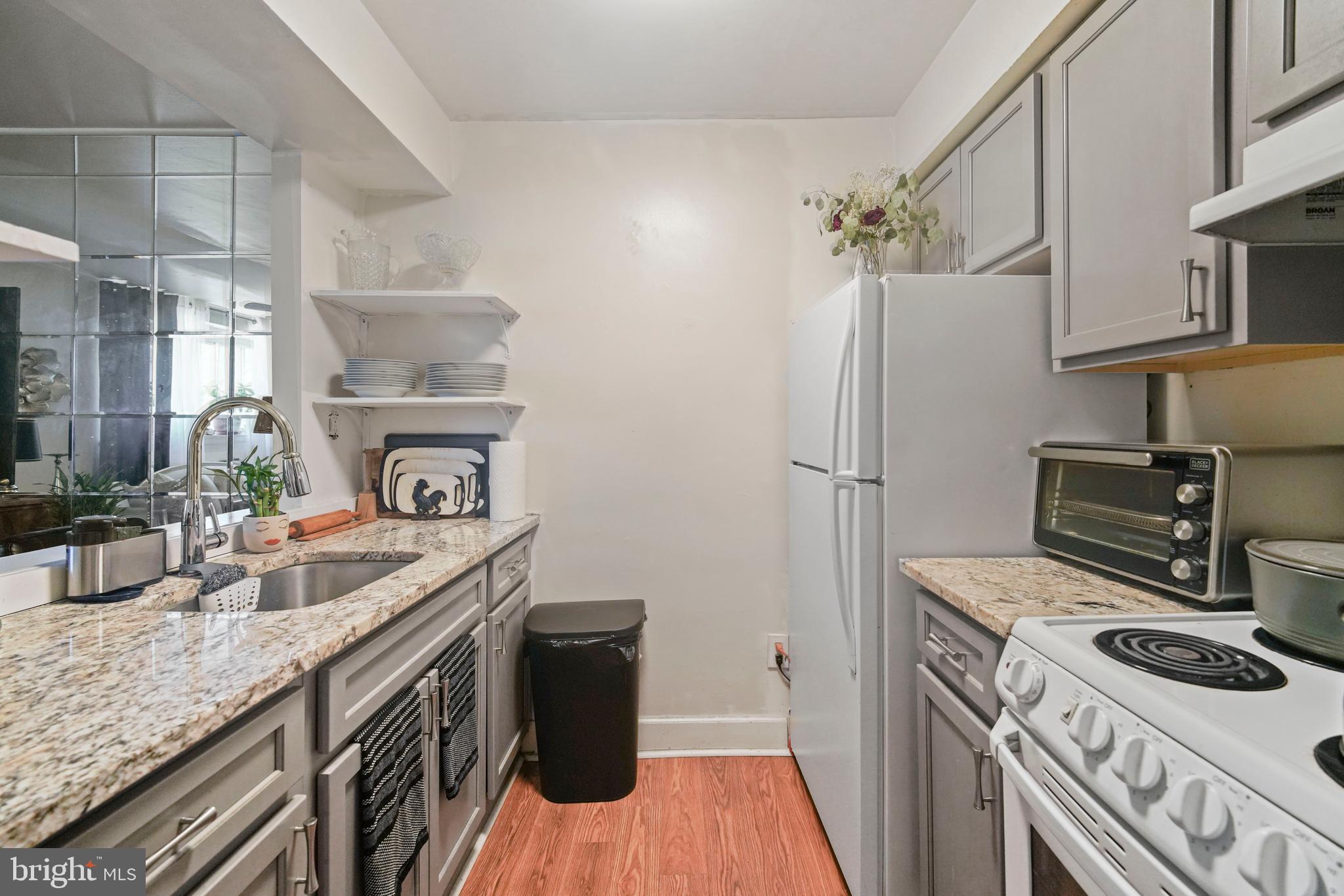 8115 West Chester Pike, Unit A8 Upper Darby, PA 19082 - Photo 11 of 17 a kitchen with stainless steel appliances granite countertop a refrigerator a stove and a sink with wooden floors