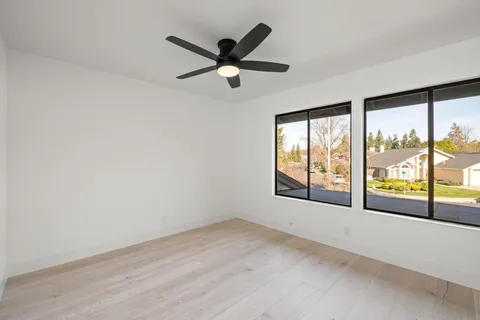 a view of empty room with wooden floor and fan
