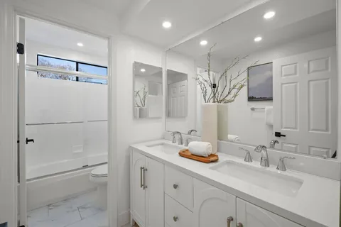 a bathroom with a double vanity sink toilet mirror and shower