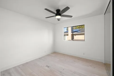 an empty room with ceiling fan and window