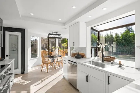a large white kitchen with a large window and stainless steel appliances