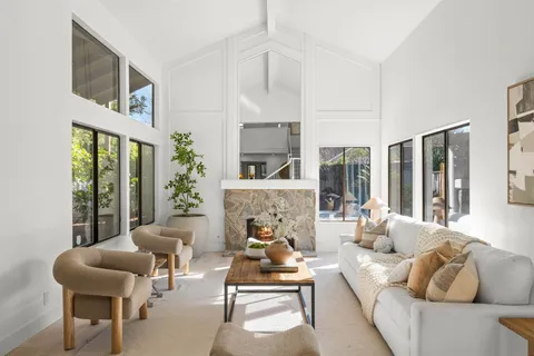 a living room with furniture fireplace and large windows