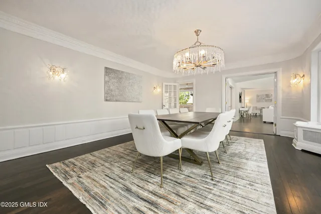 a dining room with wooden floor a chandelier a wooden table and chairs