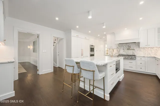 a large white kitchen with lots of counter space wooden floor and appliances