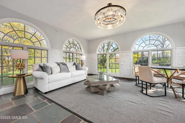 a living room with furniture a chandelier and a large window