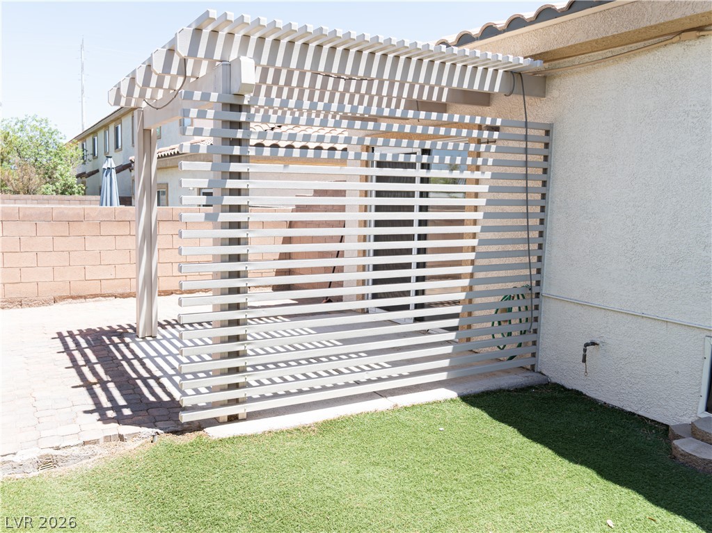 1466 Orange Jubilee Road Henderson, NV 89014 - Photo 13 of 15 A private backyard retreat features a modern slatted pergola and low-maintenance artificial turf.