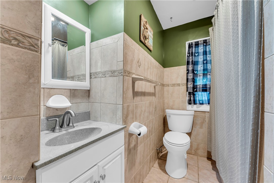 7479 Macedonia Road Bedford, OH 44146 - Photo 29 of 42 Bathroom featuring toilet, tile patterned floors, vanity, tile walls, and a shower with shower curtain