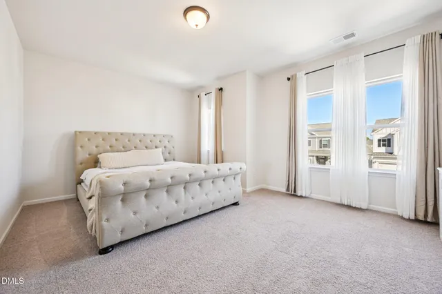 a bed sitting in a spacious bedroom next to a window