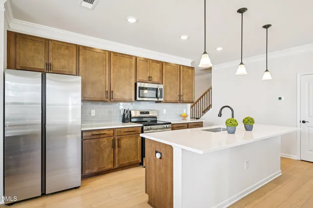 a kitchen with stainless steel appliances granite countertop a sink a stove a refrigerator a center island and cabinets