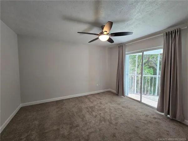 an empty room with a ceiling fan and window