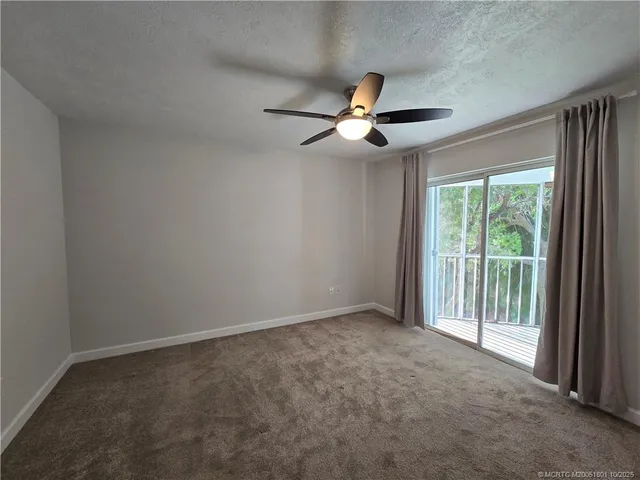 an empty room with a ceiling fan and window