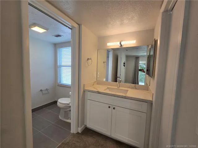 a bathroom with a granite countertop sink mirror and toilet