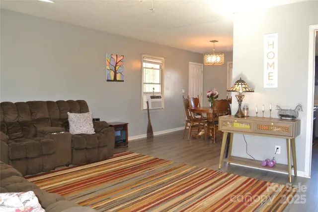 a living room with couch a dining table and painting on the wall with wooden floor