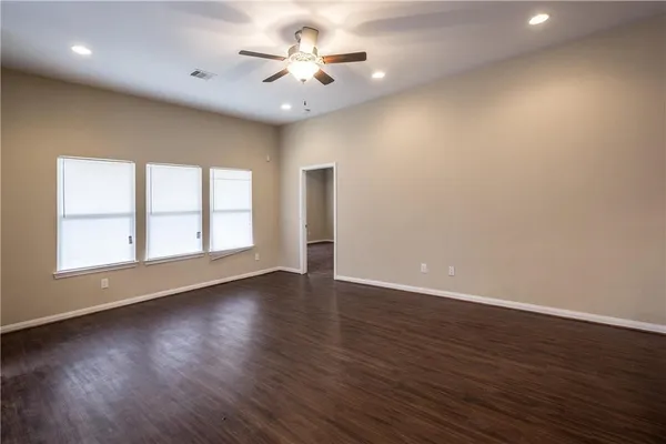 a view of an empty room with a window and wooden floor