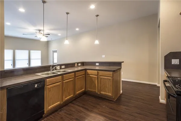 a kitchen with stainless steel appliances granite countertop a sink a stove a dining table and chairs with wooden floor