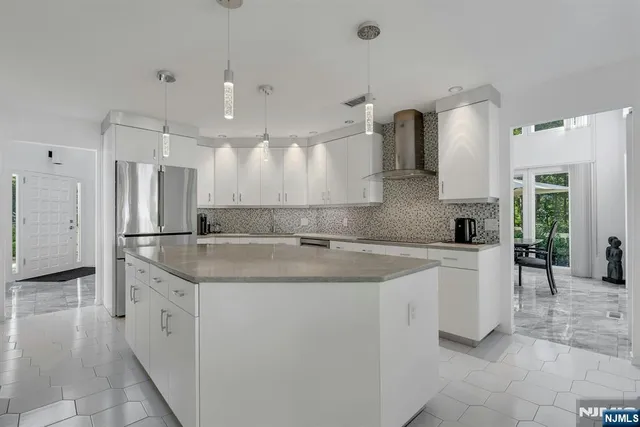 a large white kitchen with a stove a sink a refrigerator and white cabinets