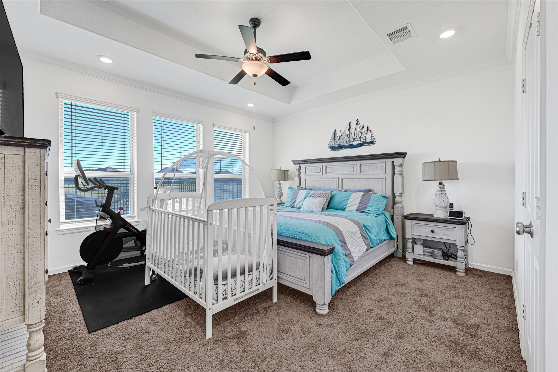 4307 Annandale Lane Rosharon, TX 77583 - Photo 9 of 31 This spacious primary bedroom on the first floor features large windows for natural light, a ceiling fan, and cozy carpeting. It shows the generous size of this room that currently accommodates a stylish bed with matching nightstands, a crib, and an exercise bike, creating a functional and inviting space that also provides a view of the water.