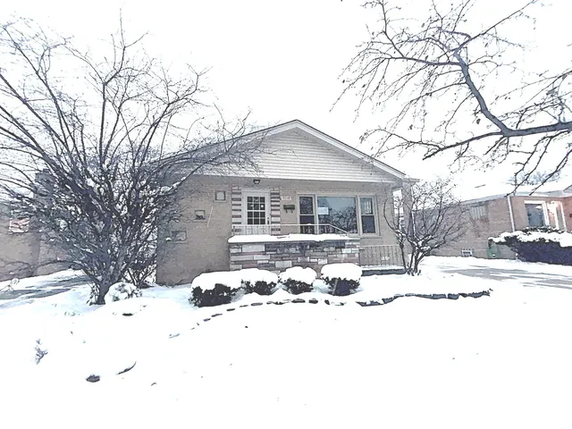 a front view of a house with a yard covered in snow