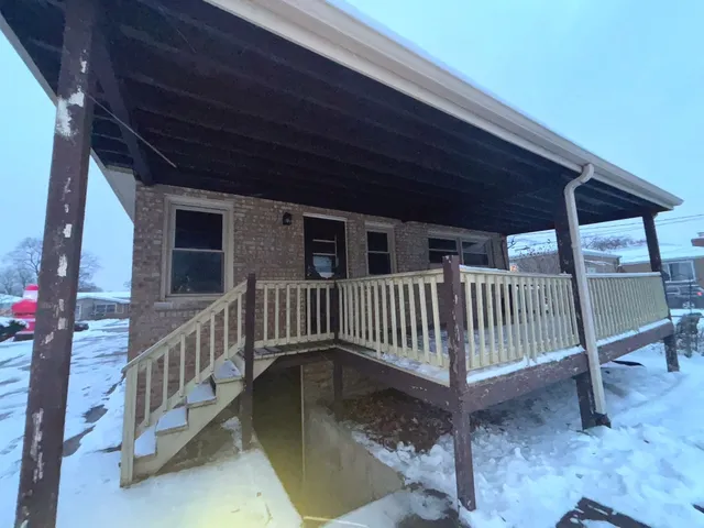 a view of a porch with a table and chairs under an umbrella with a small yard