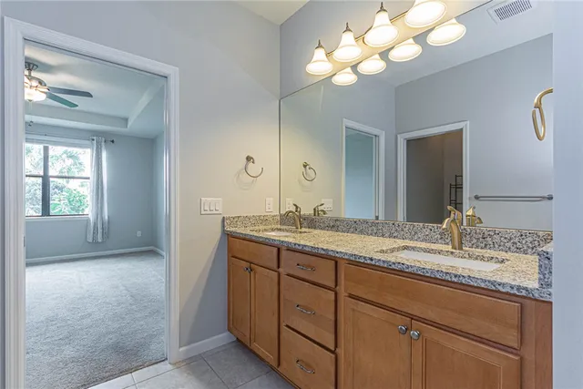 a bathroom with a granite countertop sink a large mirror and a light fixture