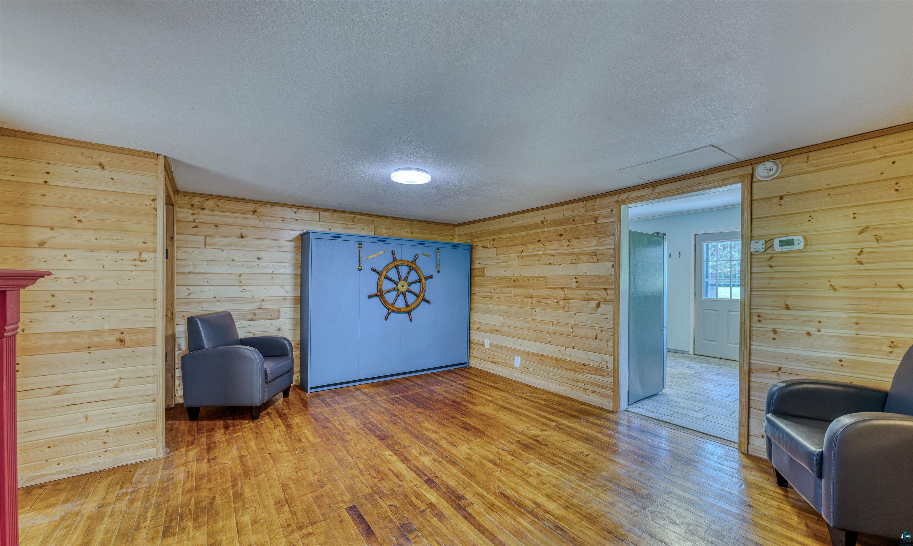 66075 Rooster Road Iron River, WI 54847 - Photo 14 of 52 Warm wood-finish flooring complements horizontal wood paneling throughout this room