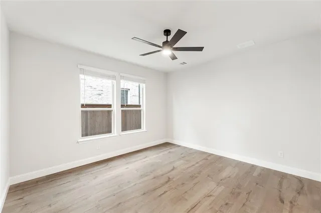 an empty room with wooden floor and ceiling fan