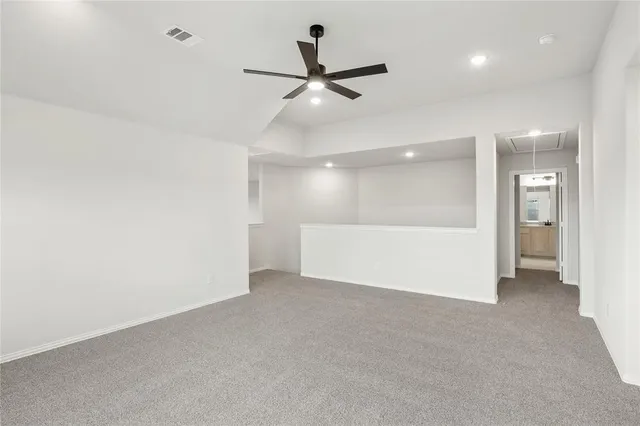 an empty room with ceiling fan and windows