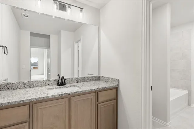 a bathroom with a granite countertop sink and a mirror