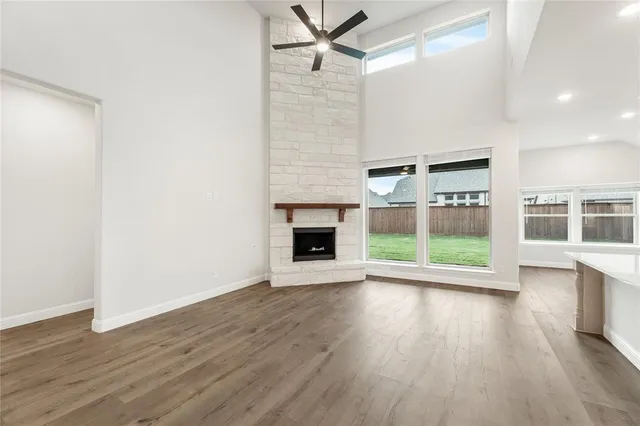 a view of an empty room with wooden floor fireplace and a window