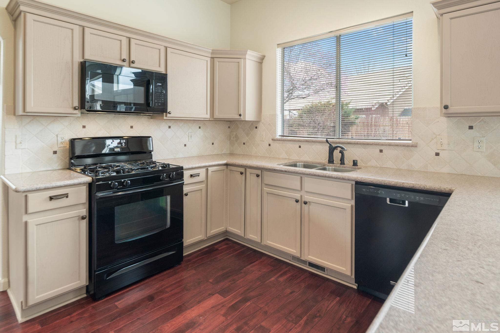 9635 Oakley Lane Reno, NV 89521 - Photo 13 of 40 a kitchen with stainless steel appliances granite countertop a sink a stove and microwave with wooden floor