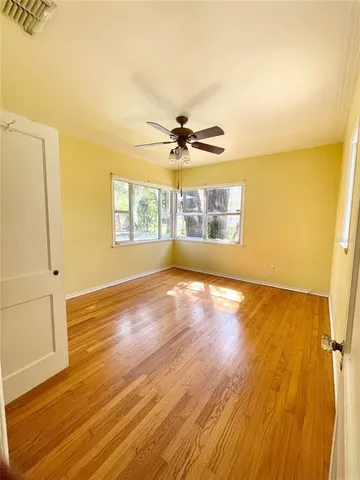 a view of an empty room with a window and wooden floor