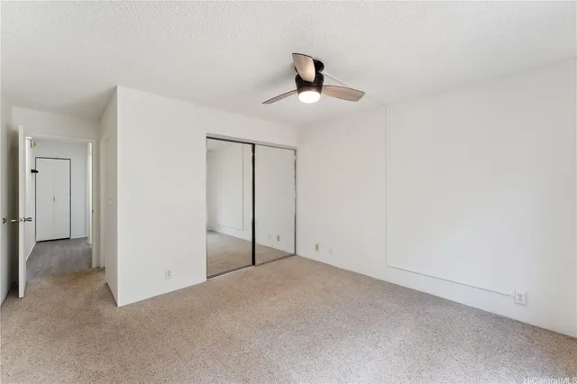 a view of an empty room and chandelier fan