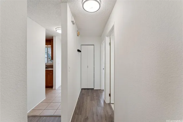 a view of a hallway with wooden floor and a bathroom