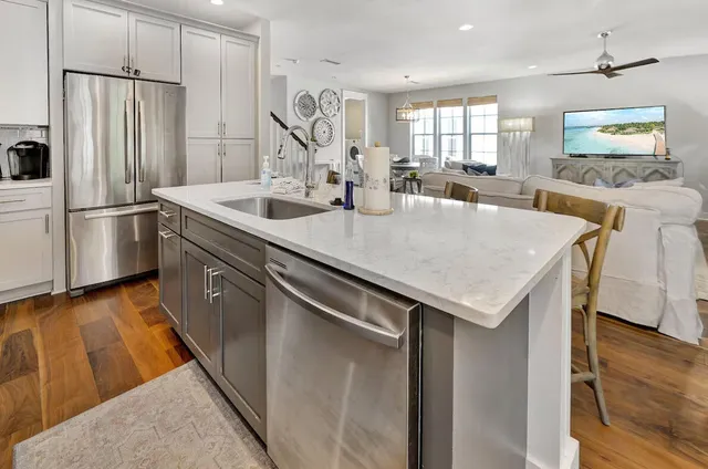 a kitchen with stainless steel appliances kitchen island granite countertop a sink a stove a refrigerator cabinets and chairs