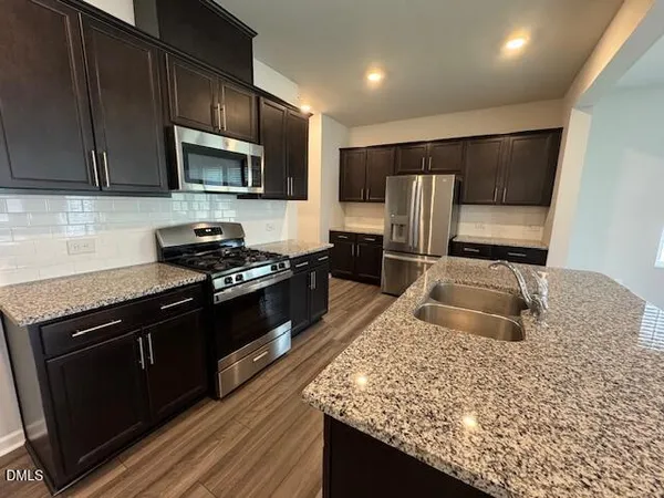 a kitchen with granite countertop wooden cabinets a stove top oven and stainless steel appliances