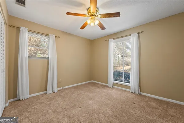 an empty room with windows and fan