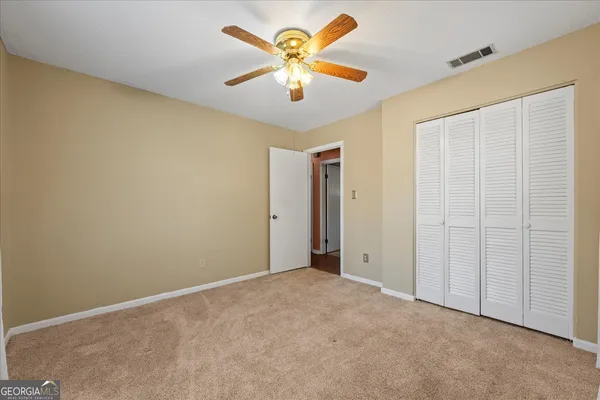 an empty room with closet and a chandelier fan