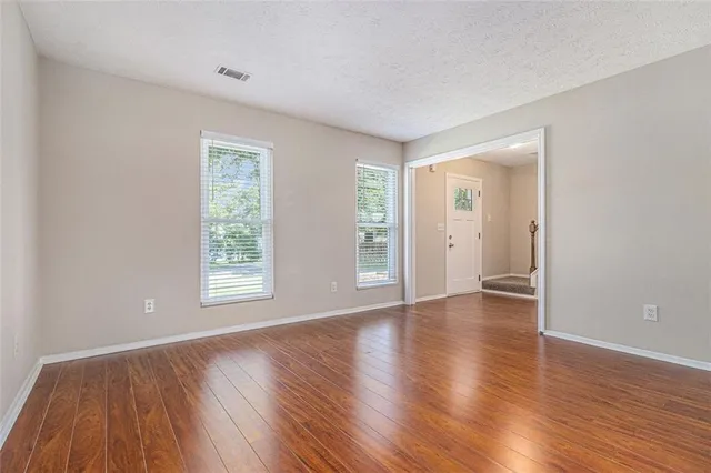 an empty room with wooden floor and windows