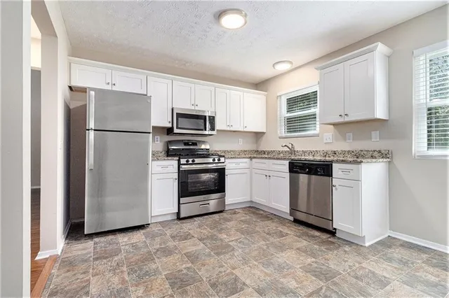a kitchen with granite countertop a refrigerator stove and sink