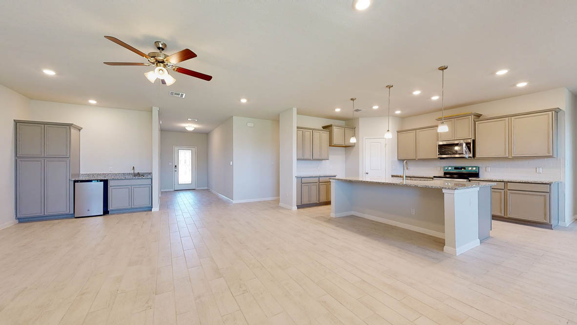 808 Gauge Road Thorndale, TX 76577 - Photo 8 of 31 An open-concept living area features a well-appointed kitchen island, a ceiling fan, and sleek wood flooring.