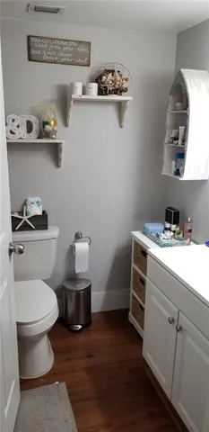 a bathroom with a toilet a sink and wooden floor